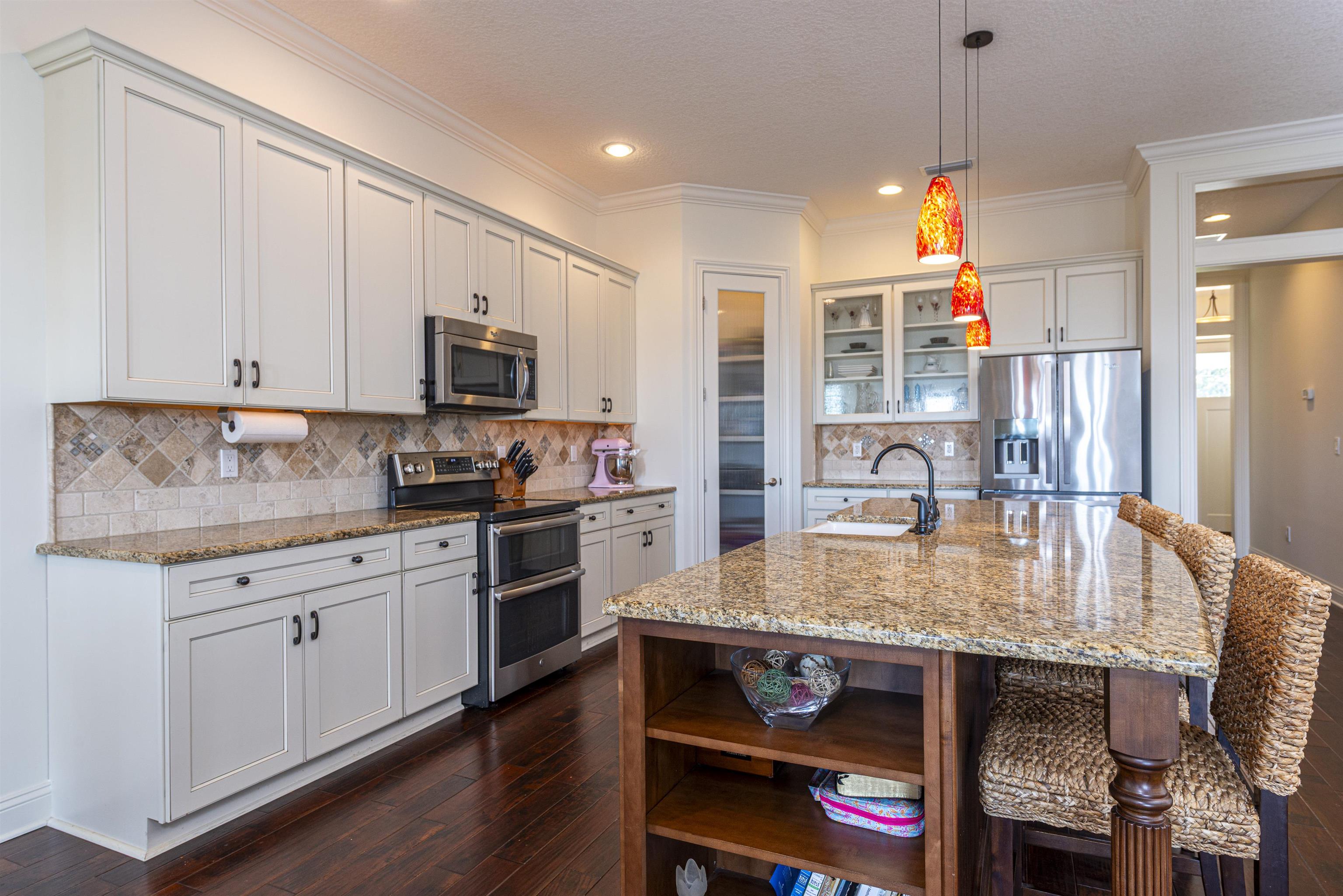 5475 Riverwood Road North St. Augustine, FL 32092 - Photo 7 of 62 Kitchen with open shelves, glass insert cabinets, appliances with stainless steel finishes, crown molding, and pendant lighting