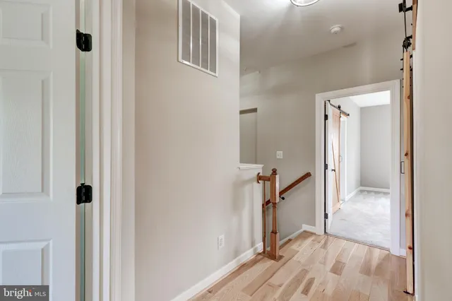 a view of a hallway with a room that has a large window and wooden floor