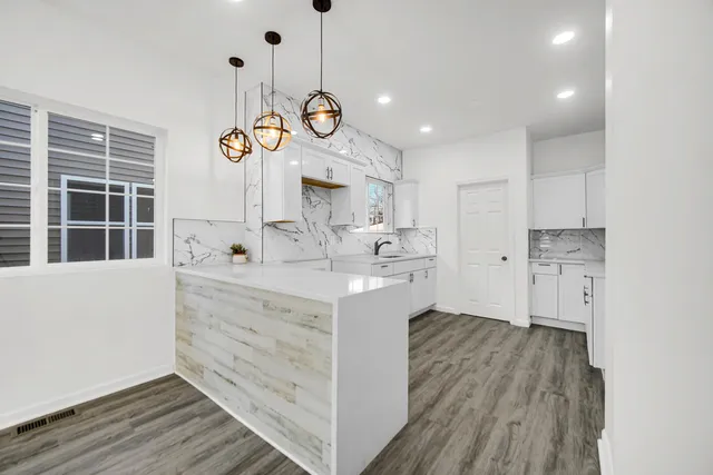 a large kitchen with kitchen island white cabinets and stainless steel appliances