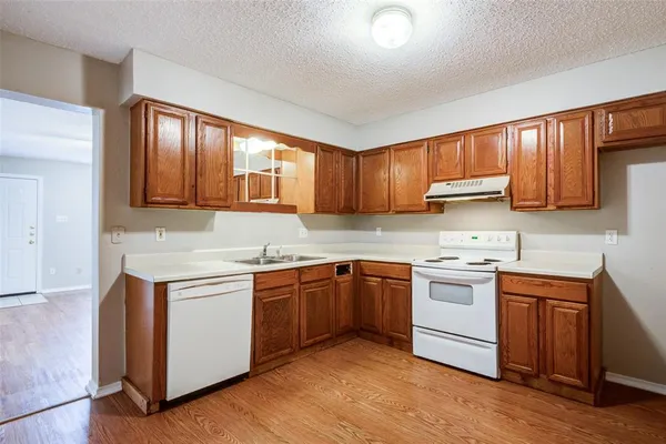 a kitchen with stainless steel appliances granite countertop wooden cabinets a sink and dishwasher a stove with wooden floor