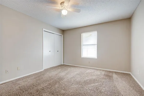an empty room with a window and a fan