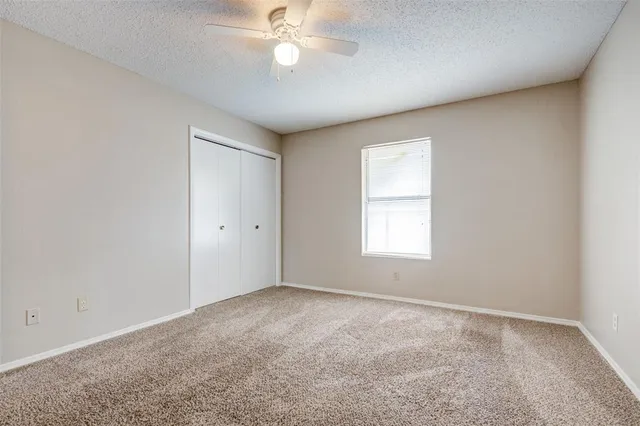 an empty room with a window and a fan