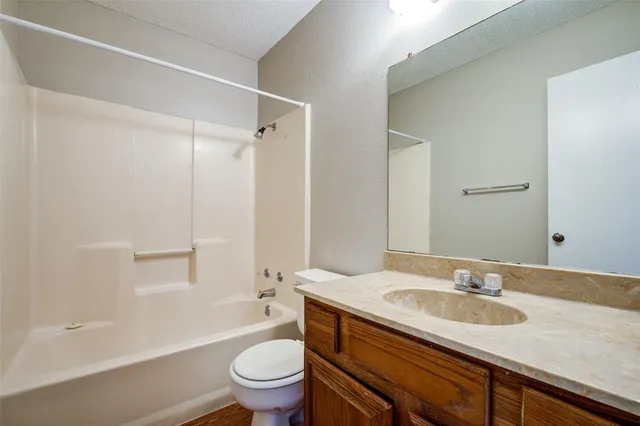 a bathroom with a granite countertop sink a toilet and shower