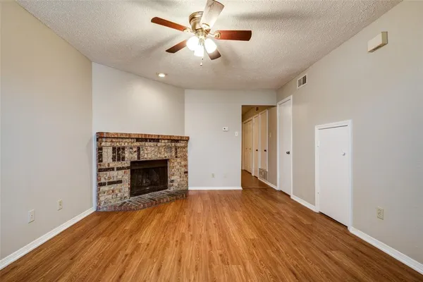 a view of an empty room with wooden floor fireplace and a window