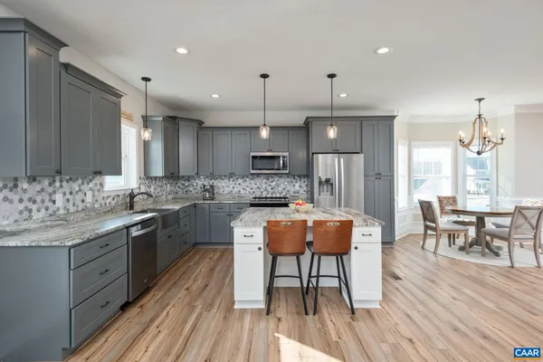 a kitchen with stainless steel appliances granite countertop a stove a sink dishwasher a dining table and chairs with wooden floor