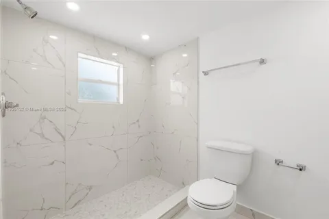 a white toilet sitting next to a shower