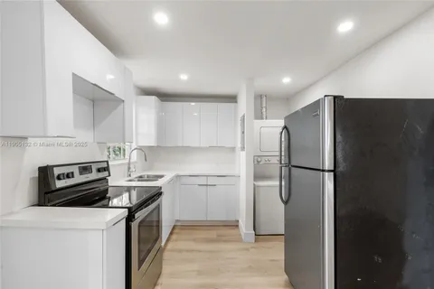a kitchen with a refrigerator a stove top oven and cabinets