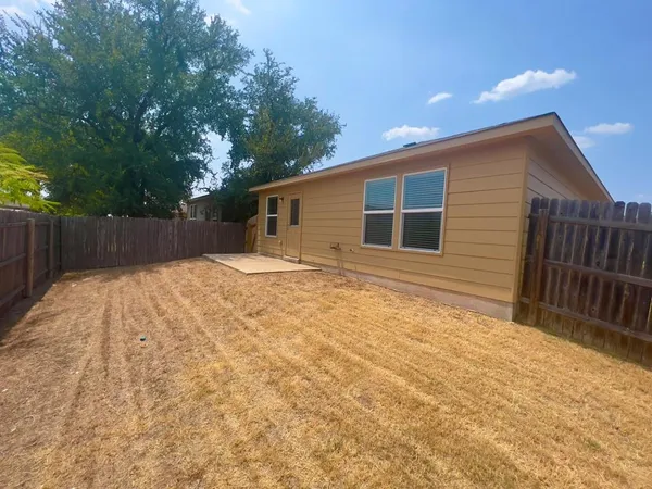 a backyard of a house with large tree and wooden fence
