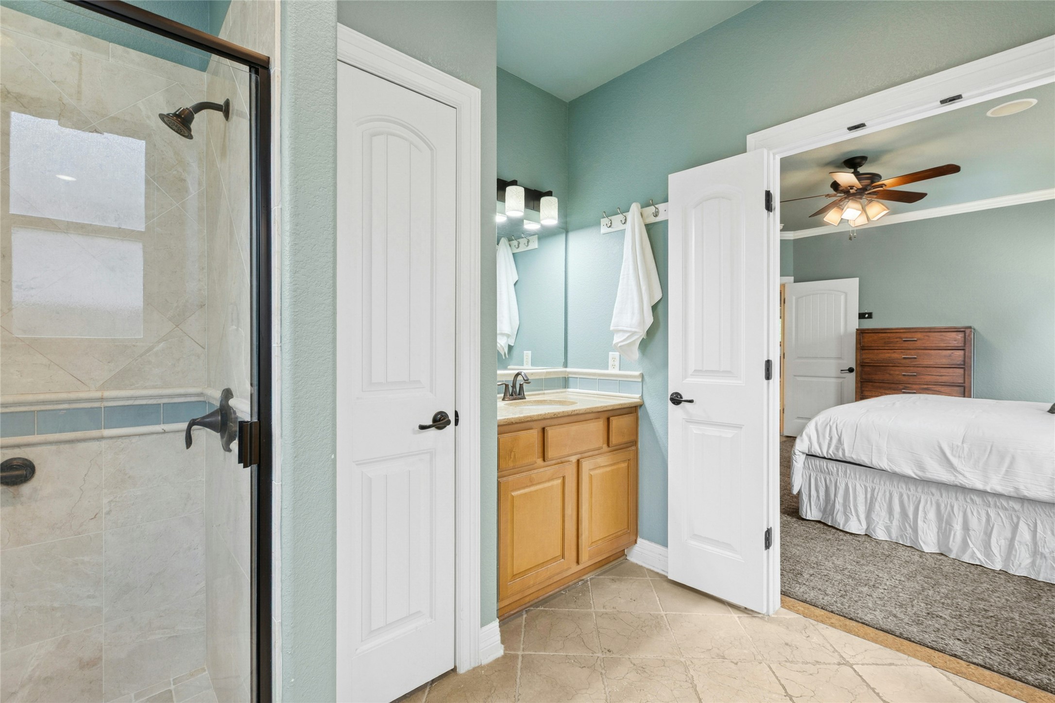 1912 Antone Street Austin, TX 78723 - Photo 19 of 38 Master bathroom with vanity, a shower stall, a ceiling fan, light colored carpet, and ornamental molding