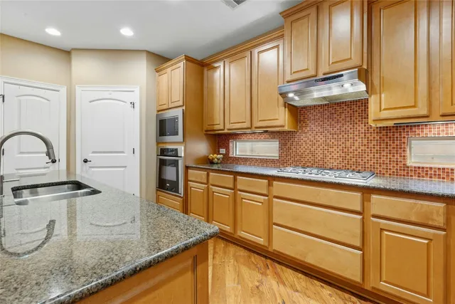 a kitchen with stainless steel appliances granite countertop a sink a stove and cabinets