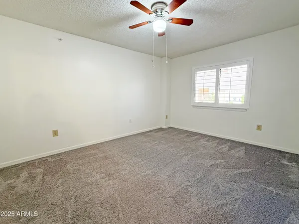 an empty room with a window and a fan