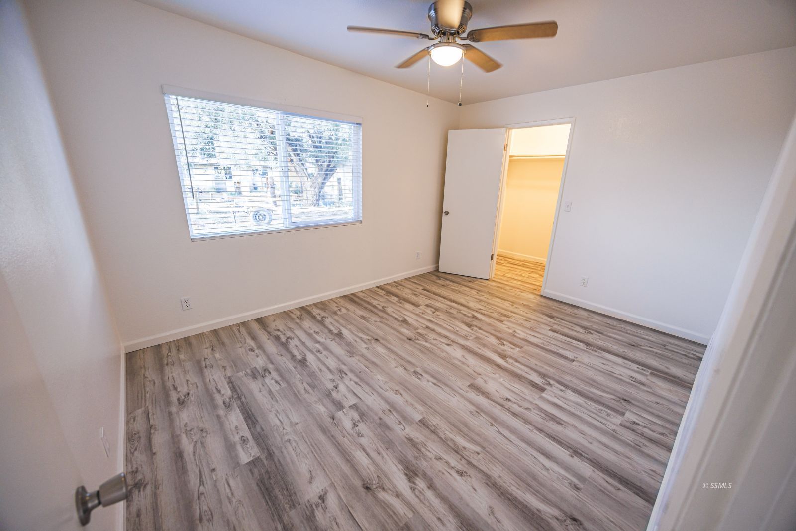 1213 Primrose Street Ridgecrest, CA 93555 - Photo 16 of 37 a view of an empty room with wooden floor and a window