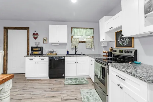 a kitchen with granite countertop a stove top oven sink and cabinets