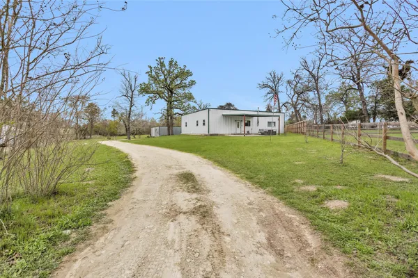 a view of a white house with a big yard and large trees