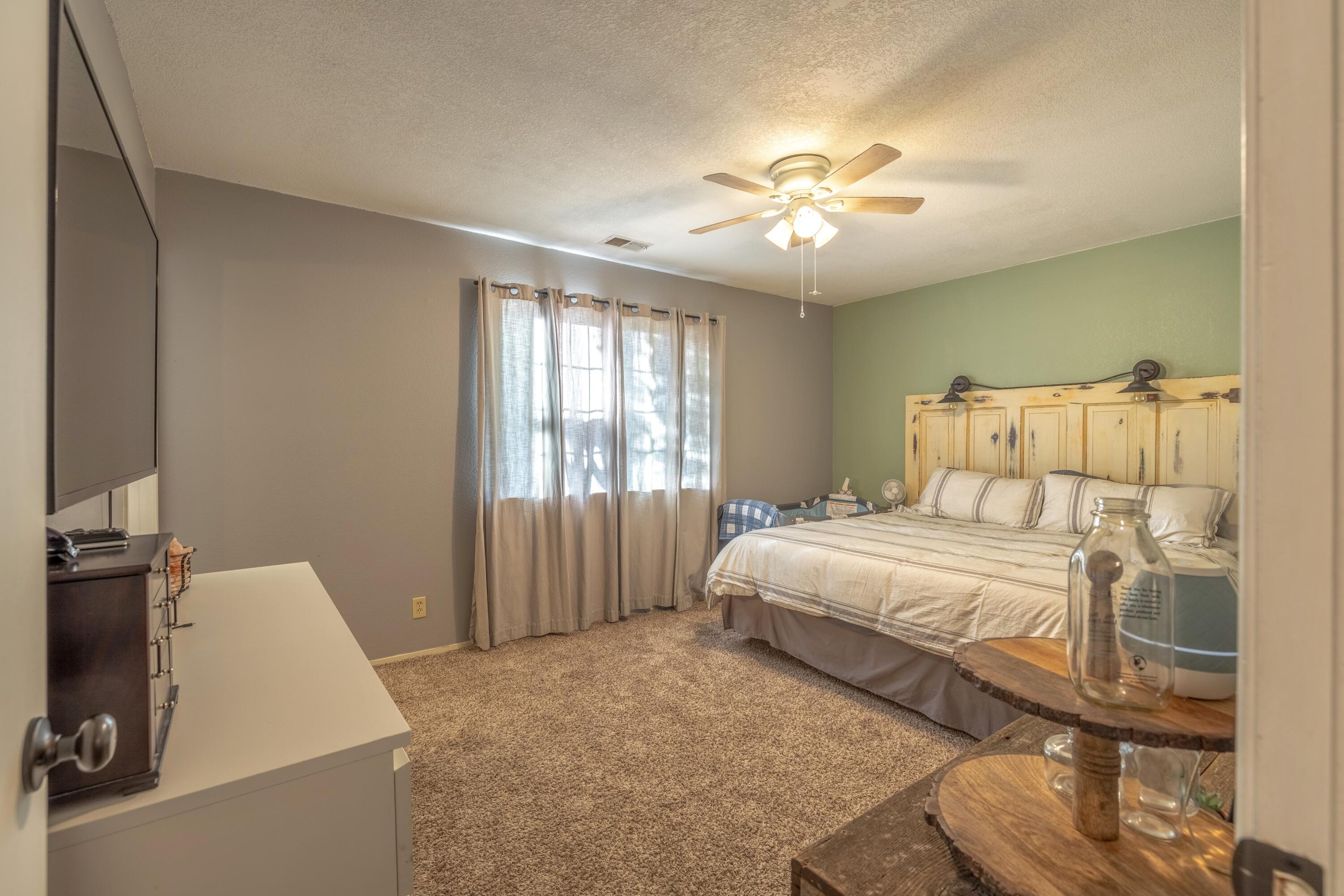 22207 Mariposa Road Tehachapi, CA 93561 - Photo 23 of 32 a spacious bedroom with a bed and a chandelier