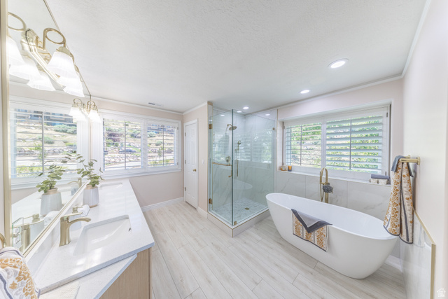 144 Bountiful Boulevard Bountiful, UT 84010 - Photo 16 of 28 Full bathroom with double vanity, a soaking tub, a shower stall, ornamental molding, and recessed lighting