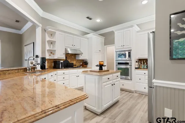 a kitchen with stainless steel appliances white cabinets and wooden floors
