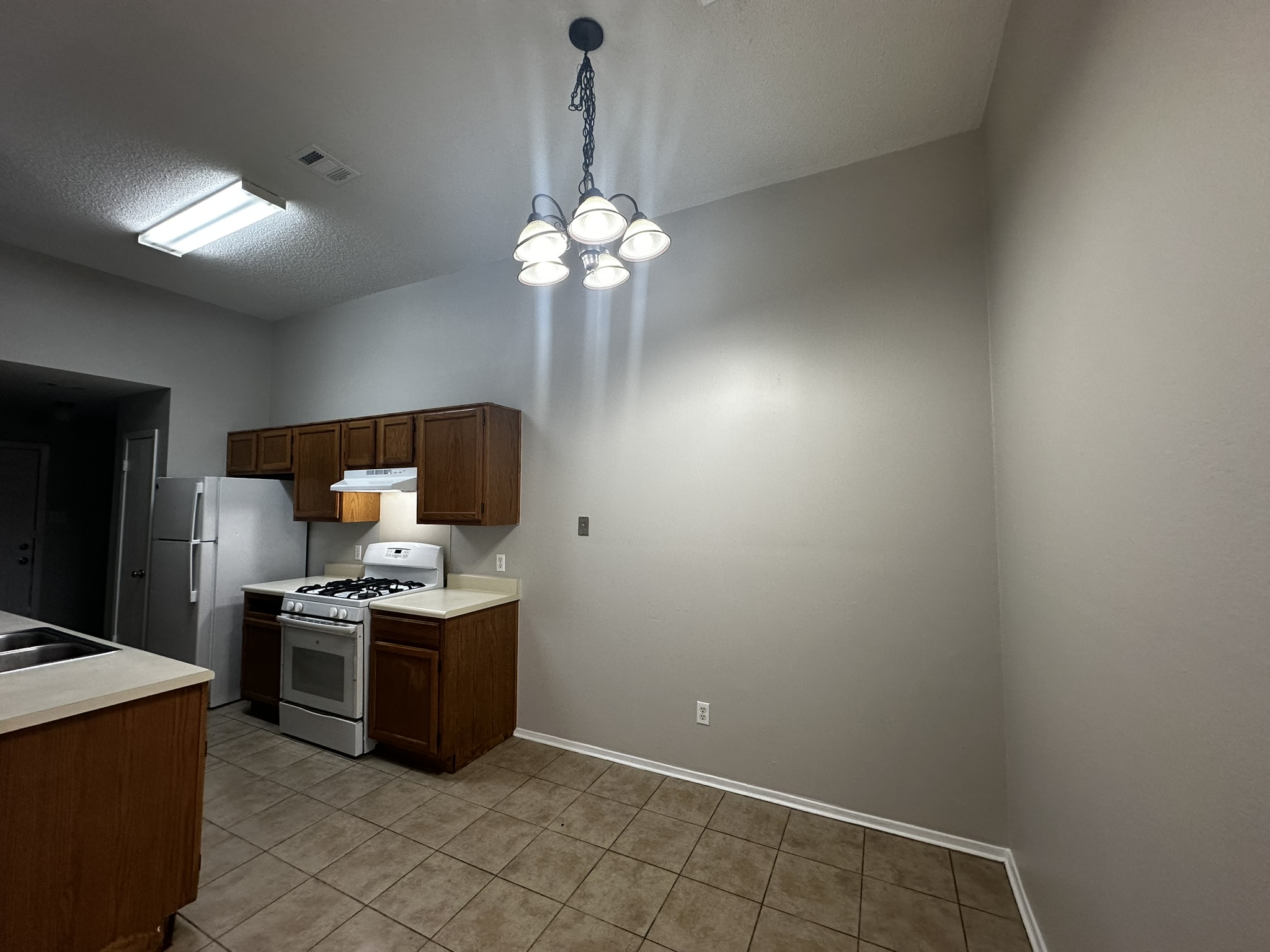 2606 Howellwood Way, Unit A Austin, TX 78748 - Photo 4 of 15 Kitchen with white range with gas stovetop, light countertops, decorative light fixtures, light tile patterned floors, and a textured ceiling
