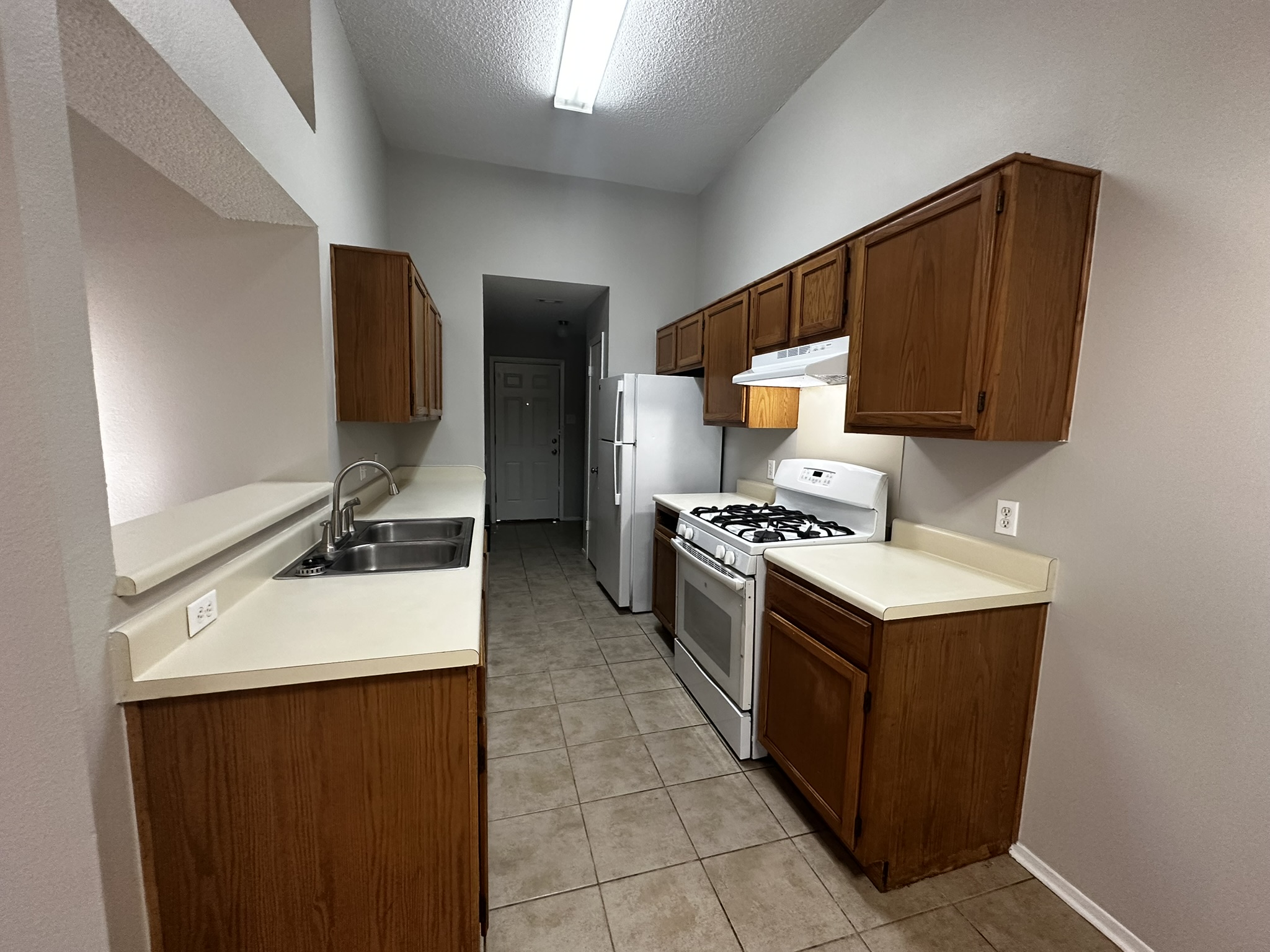 2606 Howellwood Way, Unit A Austin, TX 78748 - Photo 5 of 15 Kitchen featuring white gas range oven, light countertops, under cabinet range hood, a textured ceiling, and light tile patterned floors