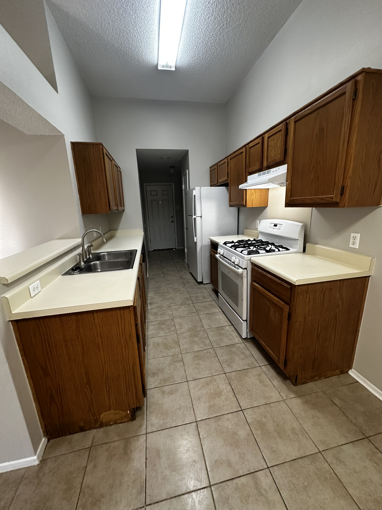 2606 Howellwood Way, Unit A Austin, TX 78748 - Photo 6 of 15 Kitchen featuring white gas stove, light countertops, a textured ceiling, under cabinet range hood, and light tile patterned floors