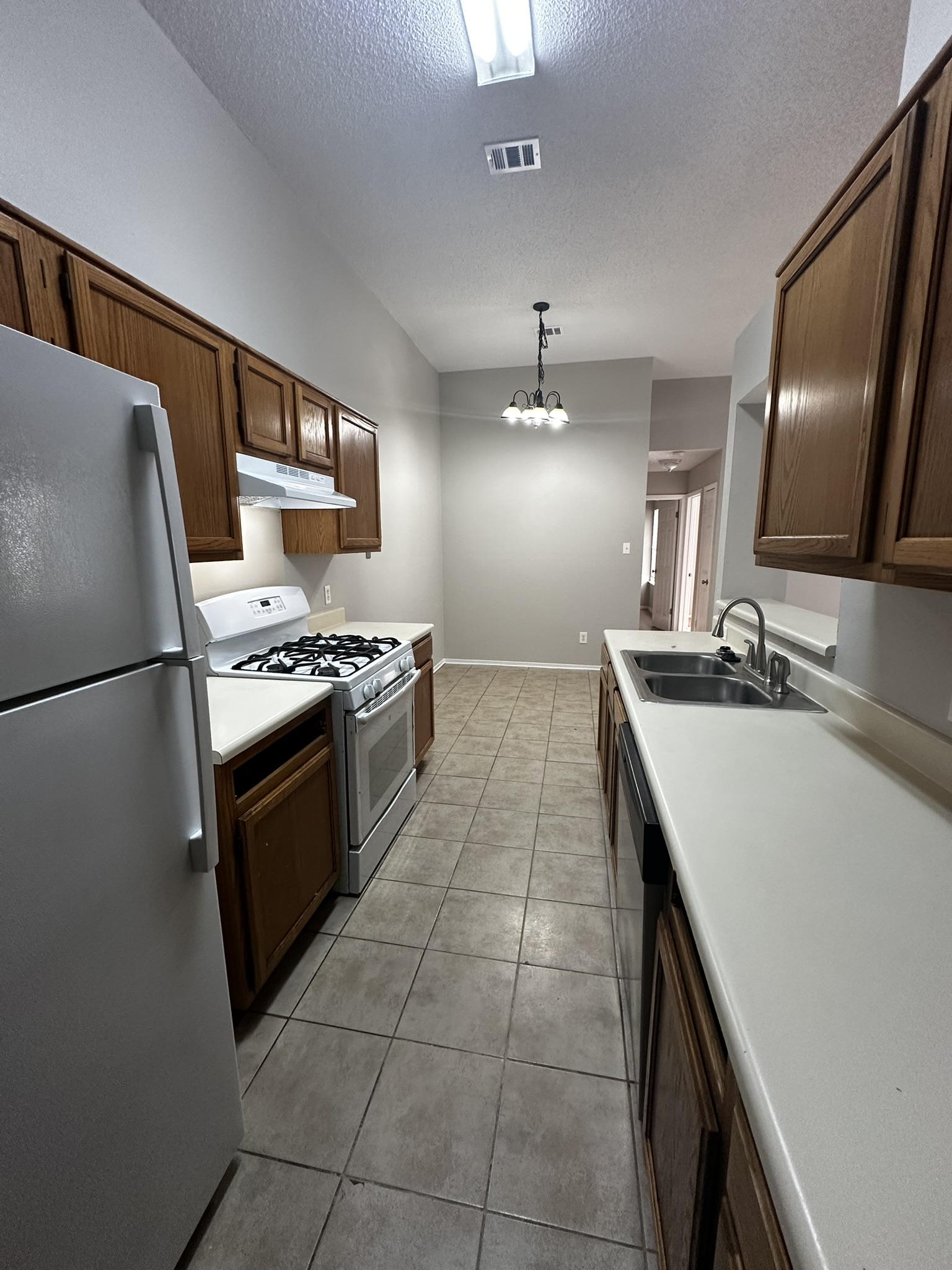 2606 Howellwood Way, Unit A Austin, TX 78748 - Photo 9 of 15 Kitchen featuring white appliances, a textured ceiling, pendant lighting, light countertops, and light tile patterned floors