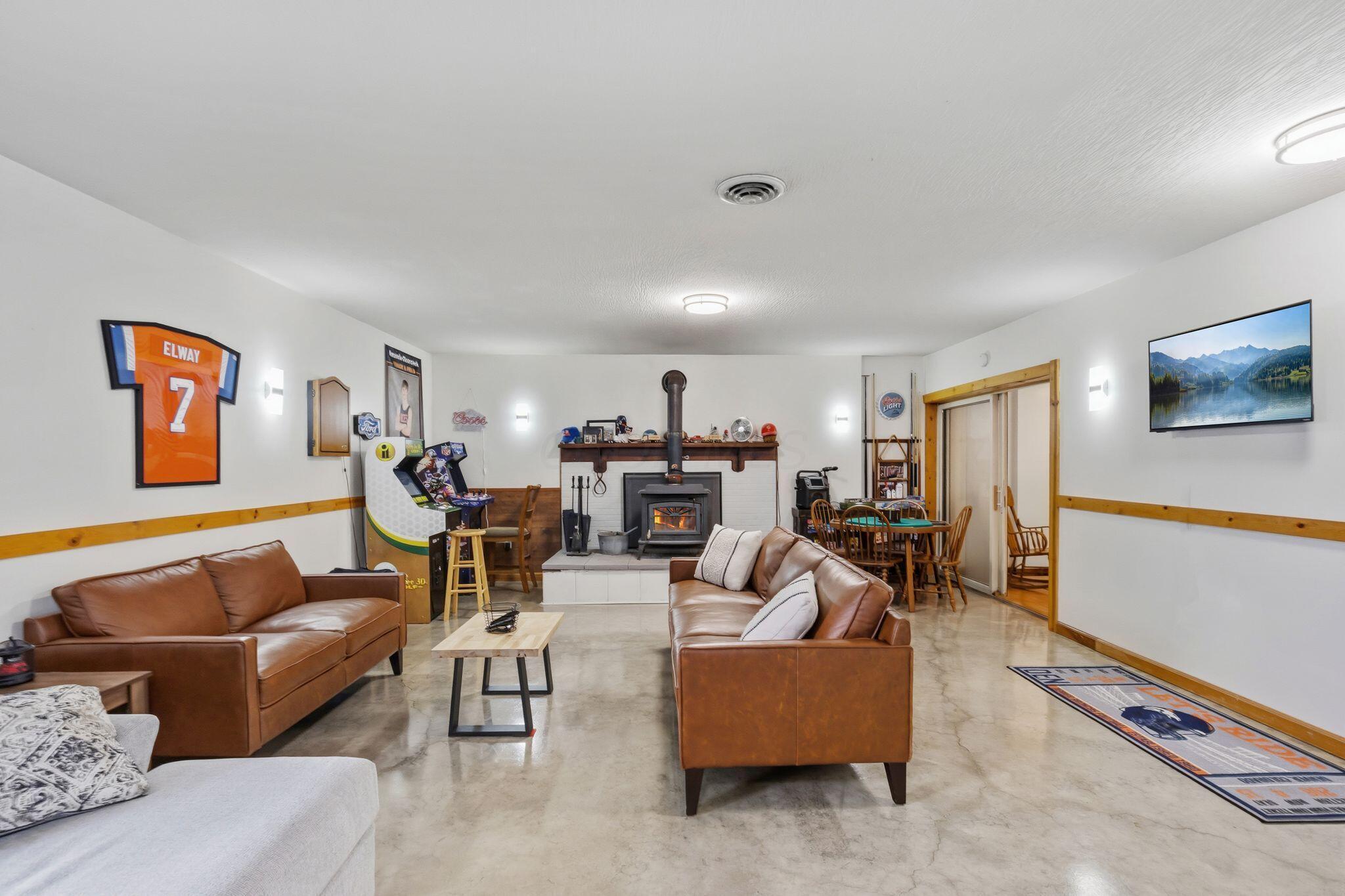 10446 Rich Hollow Road Southwest Lancaster, OH 43130 - Photo 2 of 83 Spacious living area featuring a central wood-burning stove on a raised hearth, concrete flooring, and a natural wood chair rail