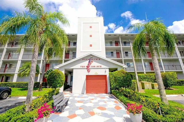 a front view of a multi story residential apartment building with a yard and potted plants