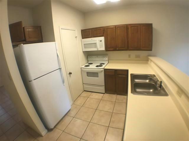 2216 San Gabriel Street, Unit 108 Austin, TX 78705 - Photo 6 of 9 Kitchen featuring light countertops, a sink, light tile patterned floors, and white appliances