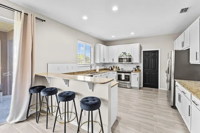 a kitchen with granite countertop kitchen island white cabinets and stainless steel appliances