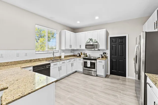 a kitchen with granite countertop white cabinets and stainless steel appliances