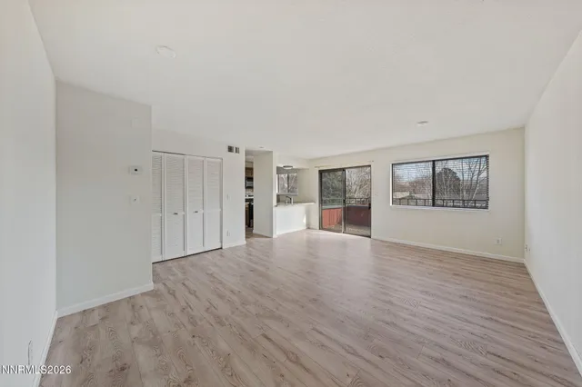 a view of an empty room with a window and a kitchen