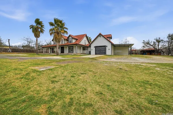a front view of a house with a yard and palm trees