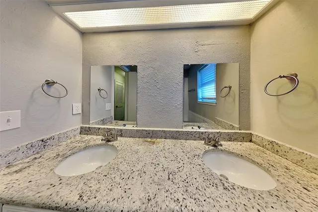 a bathroom with a granite countertop sink and a mirror