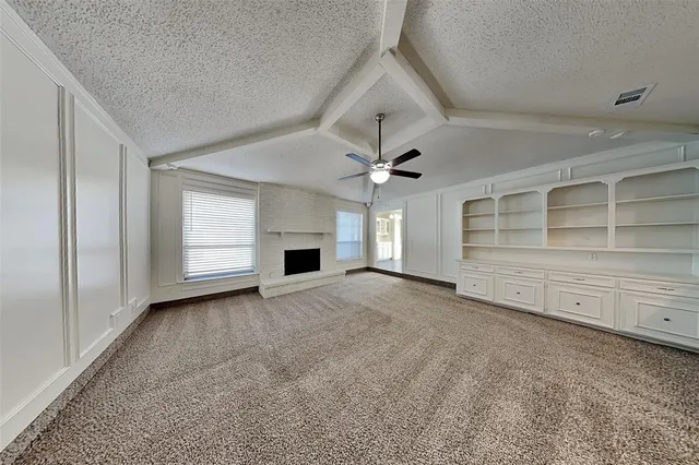 a view of an empty room with a window and fireplace