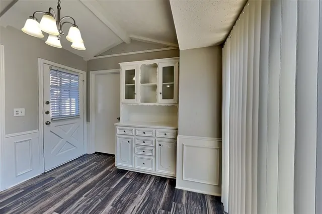 a view of a hallway with wooden floor and a kitchen