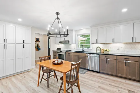 a kitchen with stainless steel appliances granite countertop a kitchen island hardwood floor sink and stove