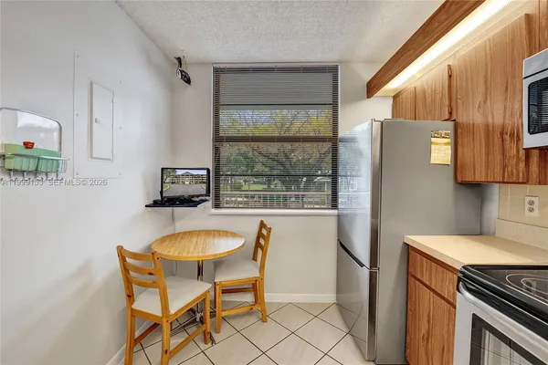 a kitchen with stainless steel appliances granite countertop a table chairs and a refrigerator