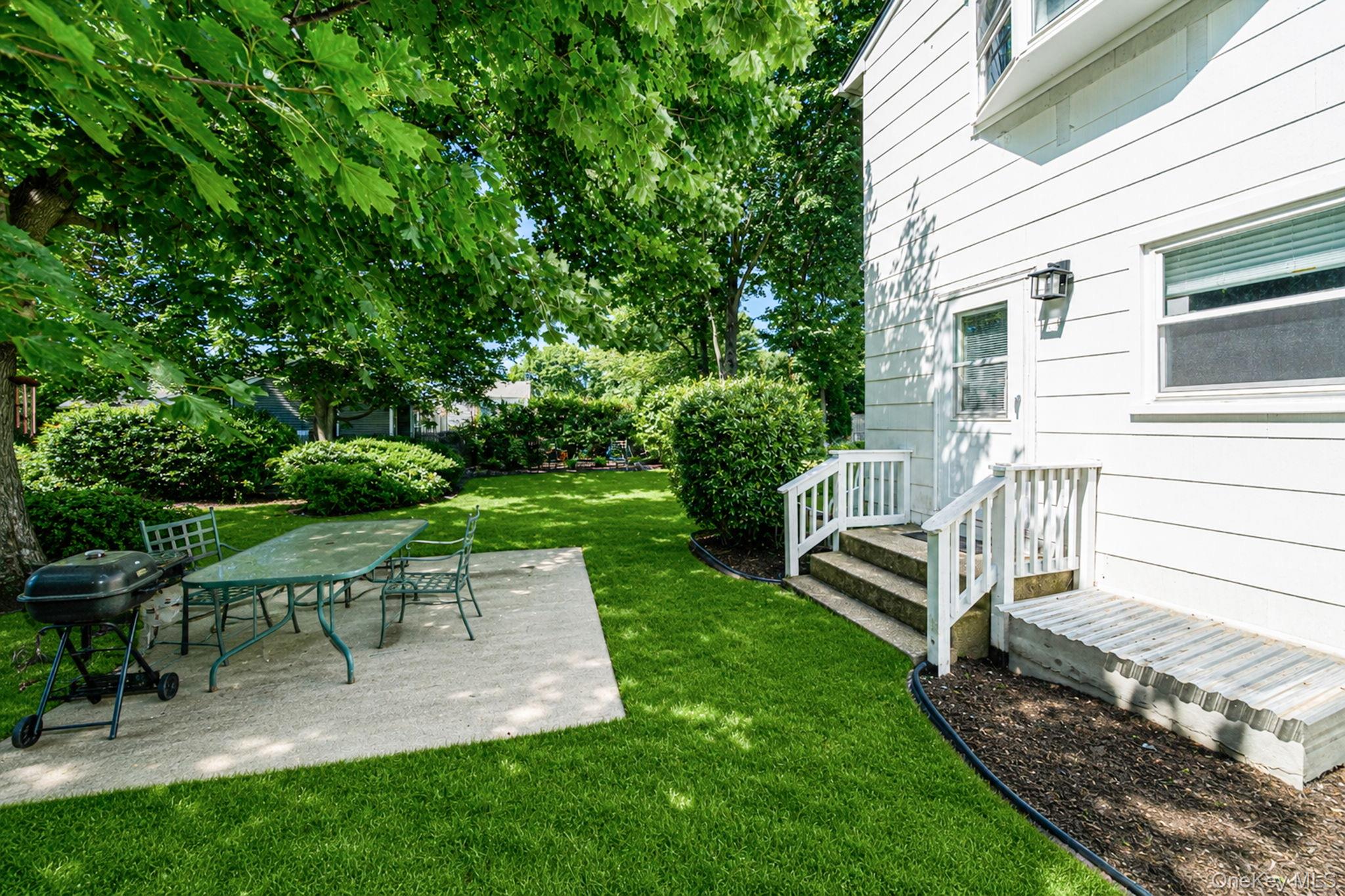31 Crooked Hill Road Huntington, NY 11743 - Photo 32 of 32 Expansive backyard featuring a lush lawn, mature trees, and a concrete patio