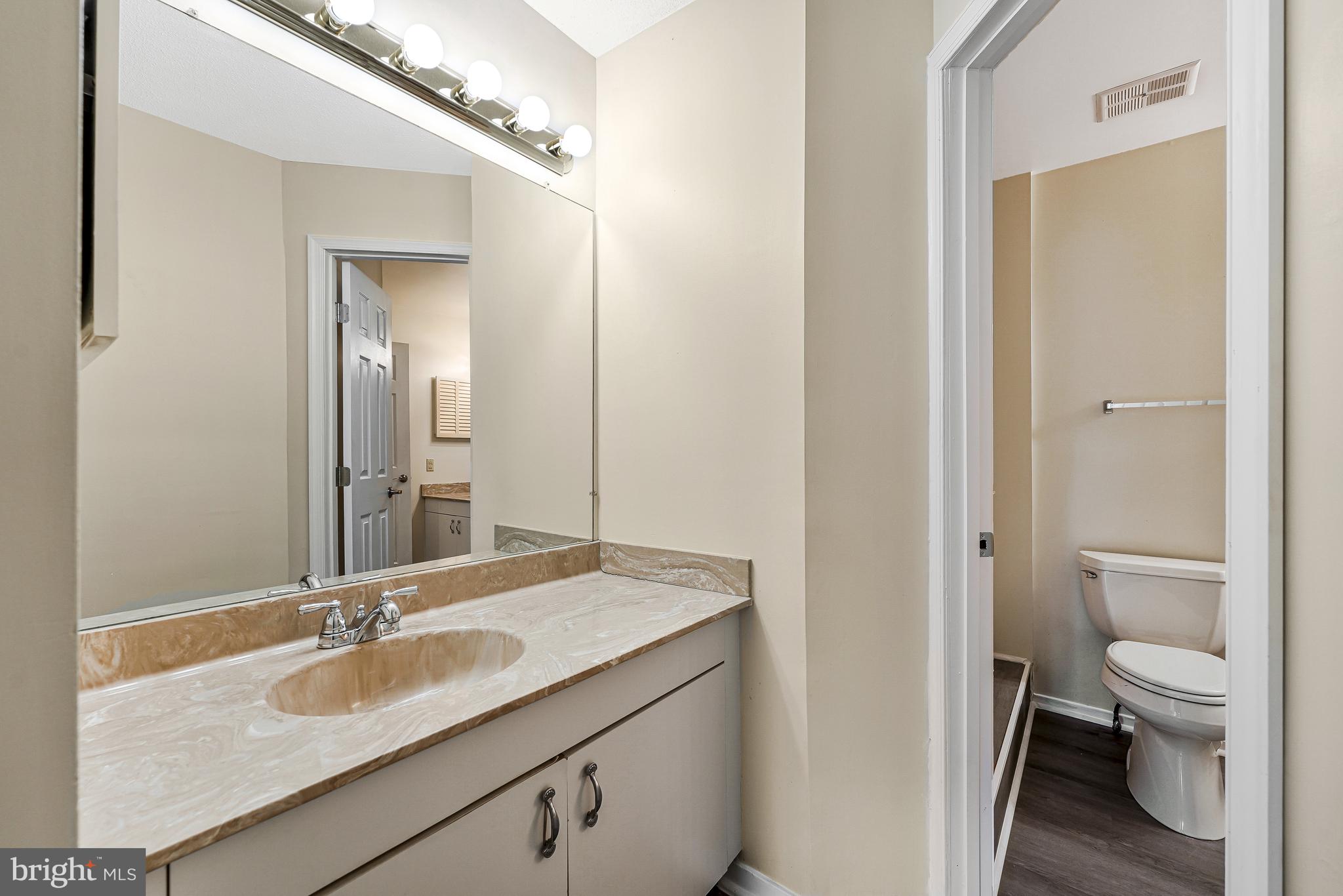 1964 Villaridge Drive Reston, VA 20191 - Photo 18 of 27 a bathroom with a granite countertop sink a toilet and a large mirror