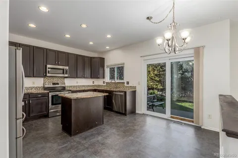 a kitchen with kitchen island granite countertop stainless steel appliances a stove refrigerator a sink and a dining table with wooden floor