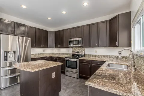 a kitchen with kitchen island granite countertop stainless steel appliances and wooden cabinets