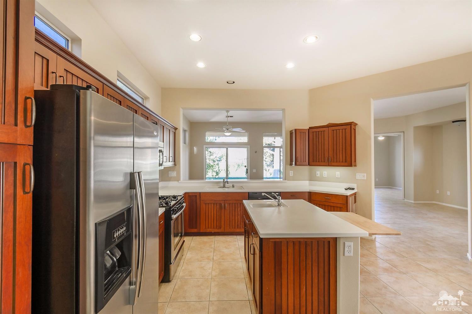 39515 Manorgate Road Palm Desert, CA 92211 - Photo 19 of 42 a dining hall with stainless steel appliances granite countertop a refrigerator a sink dishwasher and a fireplace with wooden floor
