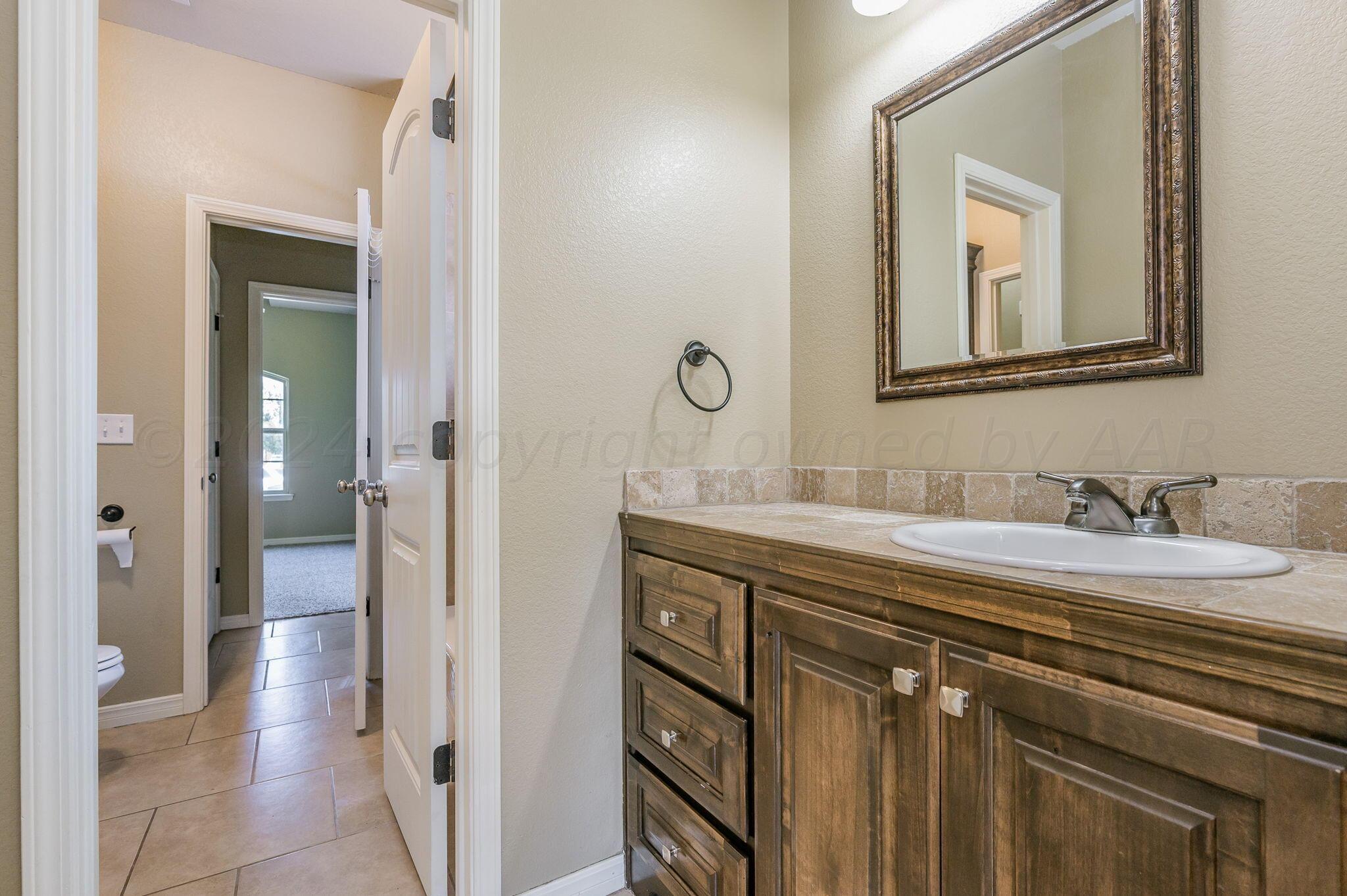 3601 Springfield Avenue Amarillo, TX 79118 - Photo 19 of 26 a en suite bathroom with a granite countertop sink and a mirror