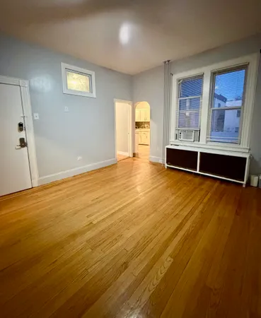 a view of an empty room with window and wooden floor