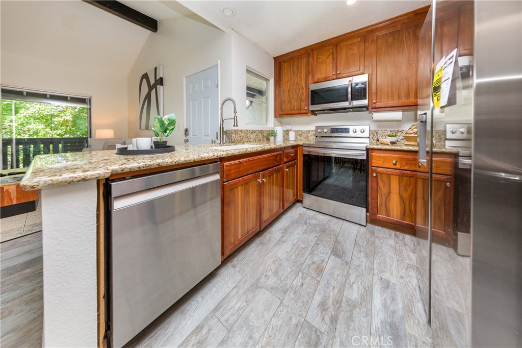 27668 Haskell Canyon Road, Unit H Saugus, CA 91350 - Photo 9 of 18 a kitchen with stainless steel appliances granite countertop a stove refrigerator sink and microwave