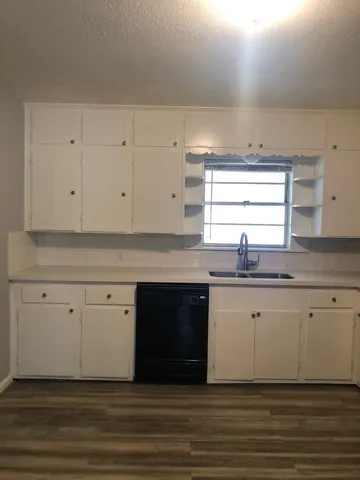 a kitchen with granite countertop white cabinets and a sink