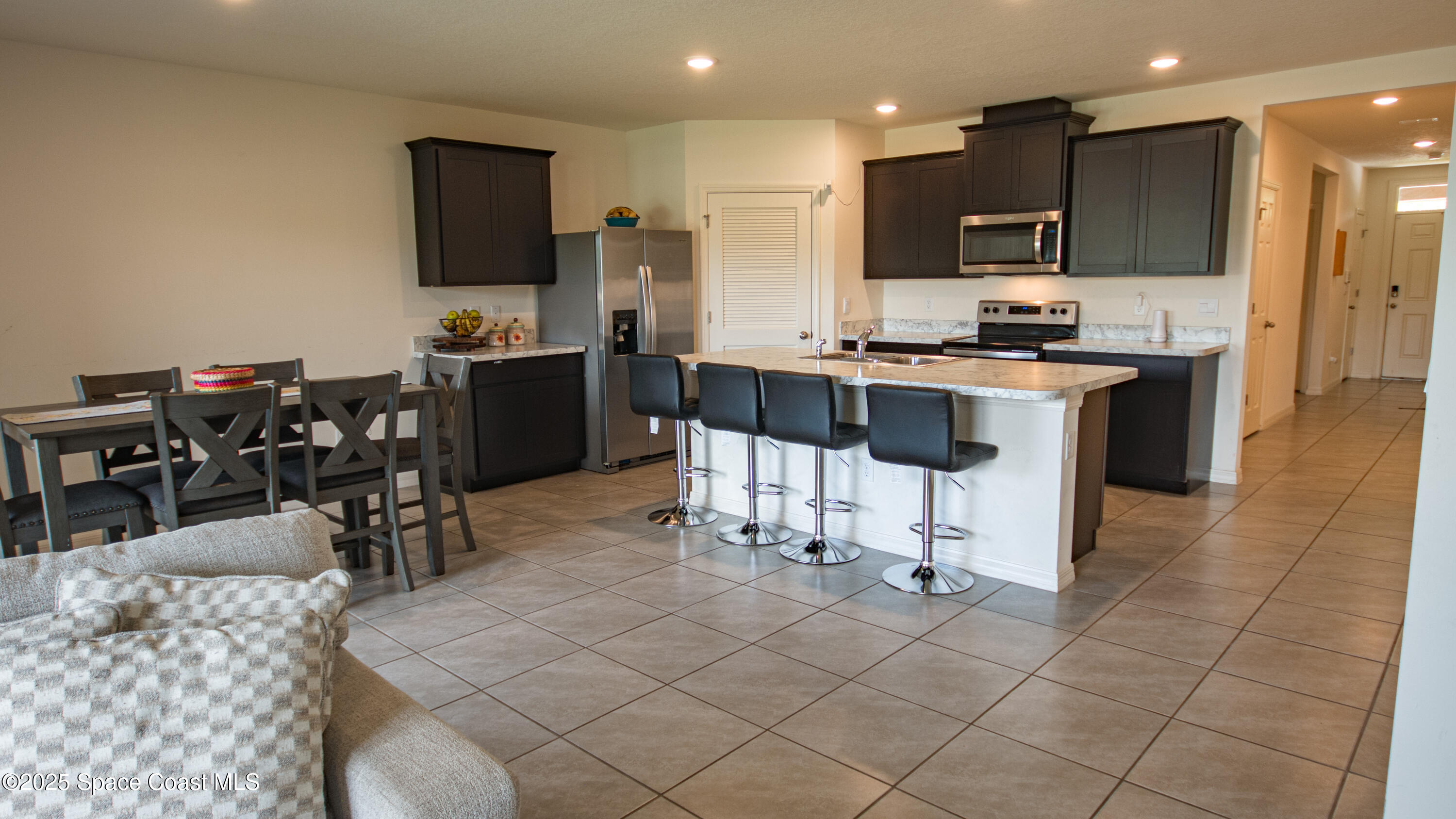 913 Trinity Street Rockledge, FL 32955 - Photo 8 of 25 a kitchen with stainless steel appliances kitchen island granite countertop a refrigerator a stove a sink a dining table and chairs with wooden floor