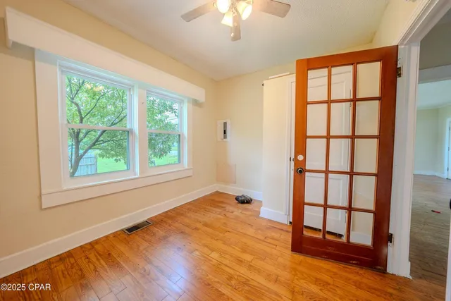 a view of an empty room with wooden floor and a window