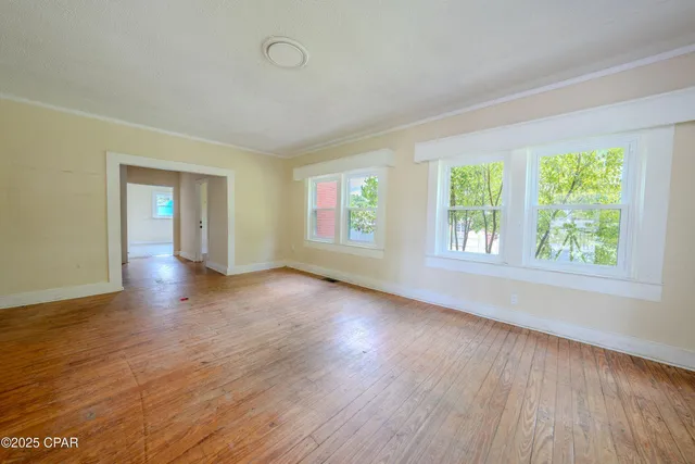 an empty room with wooden floor and windows