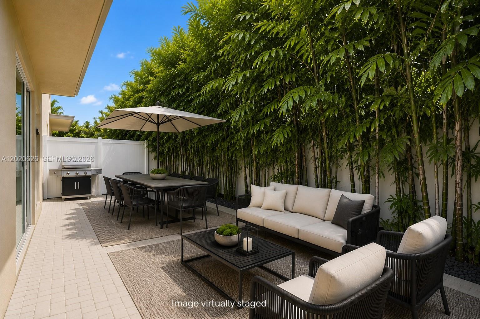 7701 Southwest 95th Terrace, Unit 1 Miami, FL 33156 - Photo 7 of 18 a view of a patio with couches table and chairs under an umbrella with a barbeque